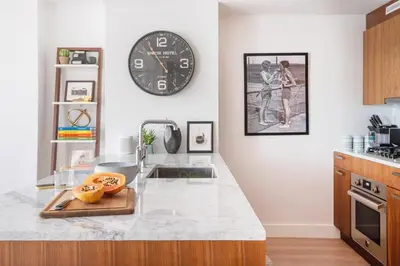 a kitchen with a large clock on the wall at Union Residence by Rove - Gorgeous Williamsburg Condo in Brooklyn