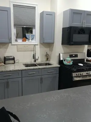 a kitchen with gray cabinets and a sink and a stove at Luxury private room bath WiFi in Troy