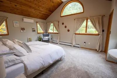 a bedroom with a large bed and two windows at Secluded Catskills Cabin , Cozy and Private in Acra