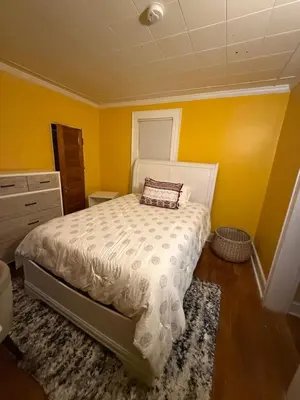 a bedroom with yellow walls and a bed with a pillow at Credo Ok! Party Room in Bridgeport