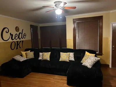 a black couch in a living room with a ceiling fan at Credo Ok! Party Room in Bridgeport