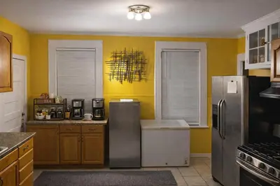 a kitchen with yellow walls and a stainless steel refrigerator at Credo Ok! Party Room in Bridgeport