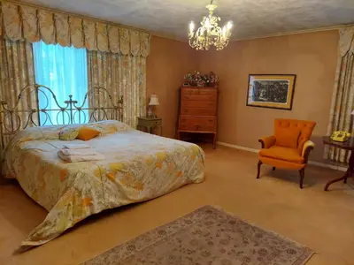 a bedroom with a bed and a chair and a chandelier at Eve's Country Retreat