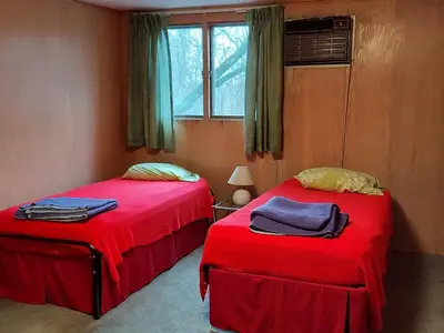 two beds in a room with red sheets and a window at Eve's Country Retreat
