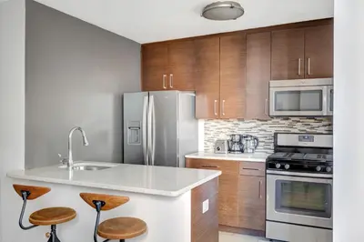 a kitchen with stainless steel appliances and wooden cabinets at Blueground Murray Hill fitness center nr East River NYC-695 in New York