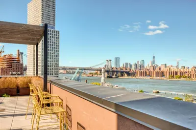 a balcony with chairs and a view of the river at Blueground Williamsburg rooftop nr East River NYC-1992 in Brooklyn