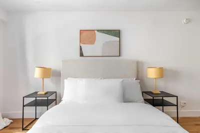 a bedroom with a white bed with two lamps at Blueground Carnegie Hill fitness center nr Central Park NYC-1967 in New York