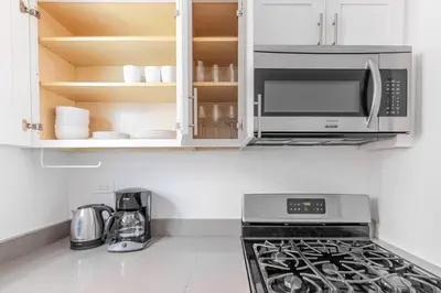 a kitchen with a microwave and a stove top oven at Blueground Carnegie Hill fitness center nr Central Park NYC-1967 in New York