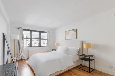 a white bedroom with a white bed and a window at Blueground Carnegie Hill fitness center nr Central Park NYC-1967 in New York