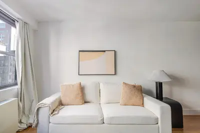 a white couch in a living room with a window at Blueground Carnegie Hill fitness center nr Central Park NYC-1967 in New York