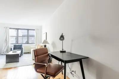 a living room with a desk and a chair at Blueground Carnegie Hill fitness center nr Central Park NYC-1967 in New York