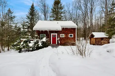 a log cabin in the snow with a red door at Greer Court Retreat in Wilmington