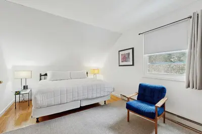 a white bedroom with a bed and a blue chair at Greer Court Retreat in Wilmington