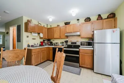 a kitchen with wooden cabinets and a white refrigerator at Cozy Townhouse Near Hunter Mountain in Tannersville