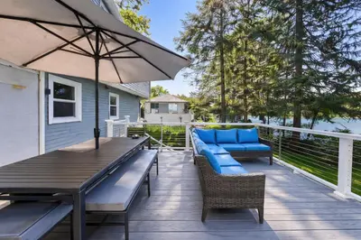 a deck with a table and chairs and an umbrella at Lakefront House 30 Min to NYC & MetLife Stadium
