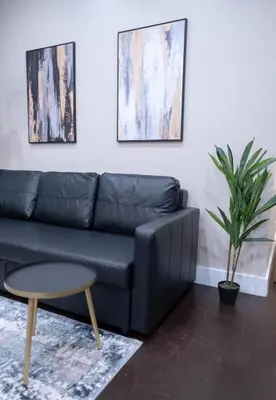 a living room with a black couch and a table at Brand New 3BR 2BA next to Central Park, elevator in New York