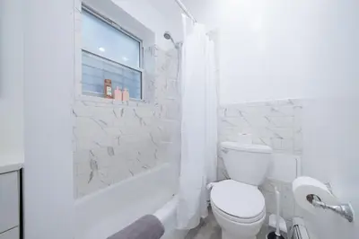 a white bathroom with a toilet and a shower at Brand New 3BR 2BA next to Central Park, elevator in New York