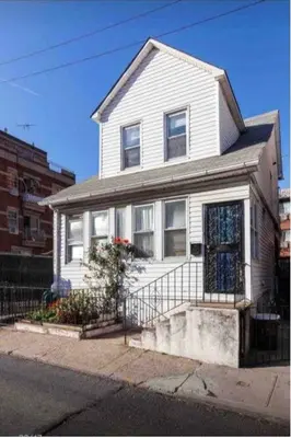a white house with a fence in front of it at Cozy private room in downtown Flushing in Queens