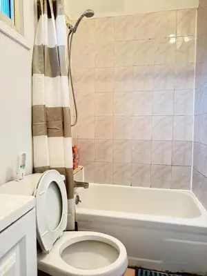 a bathroom with a toilet and a tub and a sink at Cozy private room in downtown Flushing in Queens