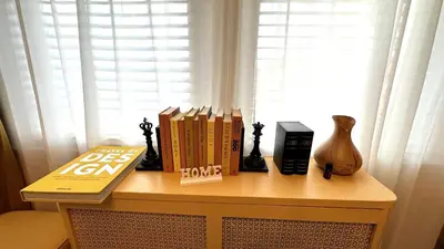 a table with books on it with a window at Sunshine Dream - Deluxe Double Room in Private House - NYC in Sunnyside