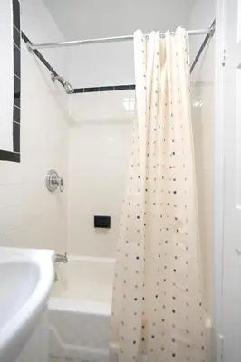 a bathroom with a shower curtain next to a bath tub at Bright & Cozy 2BD in Upper East Side in New York