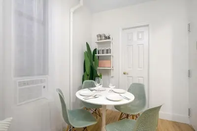 a white dining room with a white table and chairs at Bright & Cozy 2BD in Upper East Side in New York