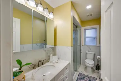 a bathroom with a sink and a toilet and a mirror at Walkable Jersey City Stay Near Parks and Dining! in Jersey City