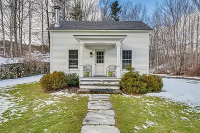 a small white house with a porch in the snow at 12 Mi to Bromley Mtn Ski Resort Quiet Hideaway in Manchester Center