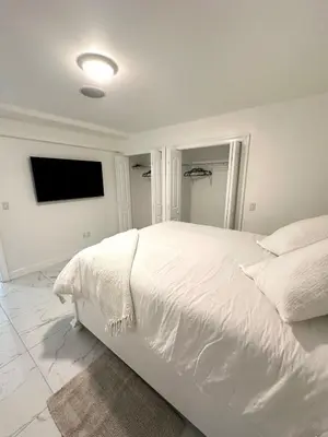 a white bedroom with a white bed and a flat screen tv at Luxury escape near New York City in Weehawken