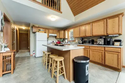 a kitchen with wooden cabinets and a island with bar stools at Mount Vision Home for Cooperstown Baseball Fams in Mount Vision
