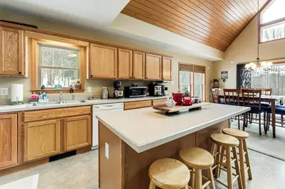 a kitchen with wooden cabinets and a island with bar stools at Mount Vision Home for Cooperstown Baseball Fams in Mount Vision
