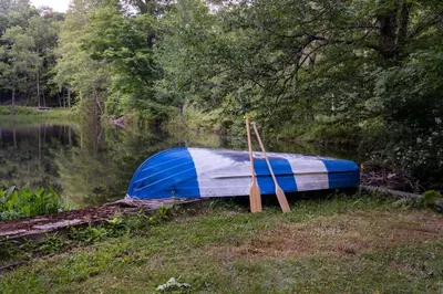 a blue and white boat sitting on the side of a lake at LaValleyEstates in Long Eddy