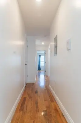 an empty hallway with white walls and wood floors at Spacious 3BR Home Near Newark Airport in Newark