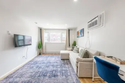 a living room with a couch and a tv at Modern 2BR 8 mins to Penn Station with WiFi and Laundry in Newark