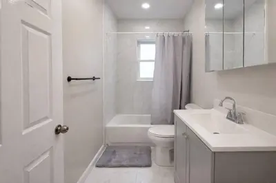 a white bathroom with a toilet and a sink at Bright Renovated 3BR Apartment w Private Entrance