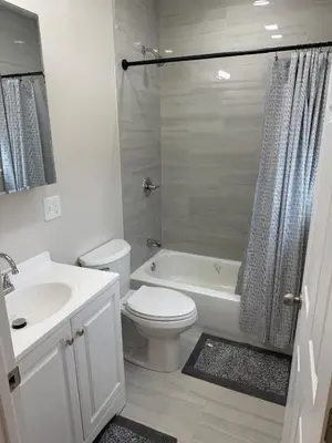 a white bathroom with a toilet and a sink at Bright Renovated 3BR Apartment w Private Entrance