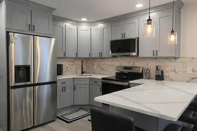 a kitchen with white cabinets and a stainless steel refrigerator at Bright Renovated 3BR Apartment w Private Entrance