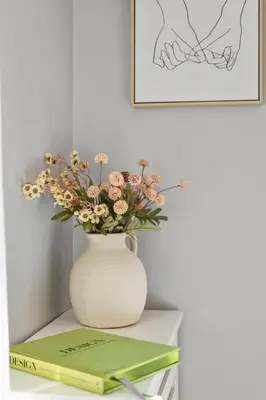 a vase with flowers on a table with a book at Minutes to Beaches - Home Theater, Couples Retreat in Milford