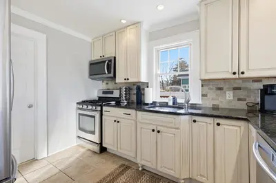 a kitchen with white cabinets and a sink and a microwave at Minutes to Beaches - Home Theater, Couples Retreat in Milford