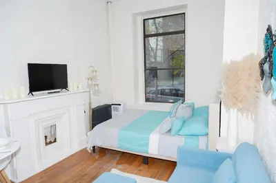 a white bedroom with a bed and a tv at Elegant84 West Side Home 5 min to Central Park in New York