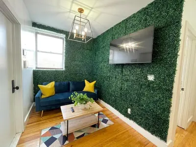 a living room with a blue couch and a green wall at Madison Ave Oasis in New York