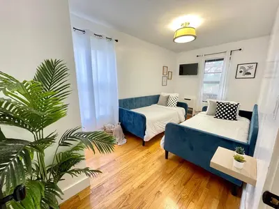 a living room with two beds and a blue couch at Madison Ave Oasis in New York
