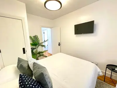 a bedroom with a white bed and a flat screen tv at Madison Ave Oasis in New York