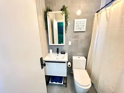a bathroom with a toilet and a sink and a mirror at Madison Ave Oasis in New York