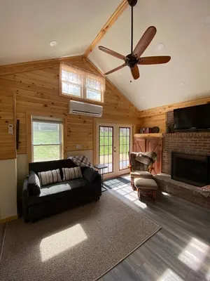 a living room with a couch and a ceiling fan at Cozy stream-side cabin in Lanesborough