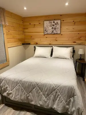 a bedroom with a large bed with wooden walls at Cozy stream-side cabin in Lanesborough
