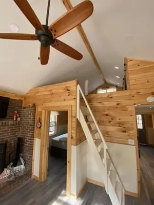 a room with a staircase and a ceiling fan at Cozy stream-side cabin in Lanesborough
