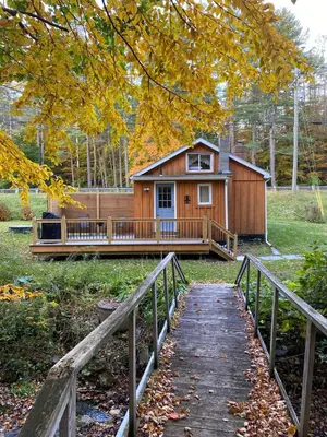 a house with a porch and a bridge leading to it at Cozy stream-side cabin in Lanesborough