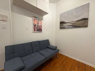 a living room with a couch and two paintings on the wall at Hudson Crown Suites in New York