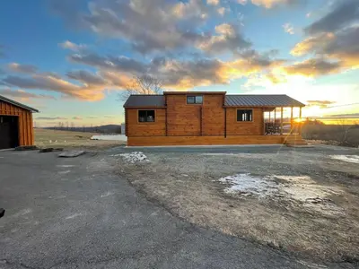 a wooden cabin with a sunset in the background at Private Luxury Log Cabin in the Endless Mountains, Firepit, Farm Charm in Kingsley